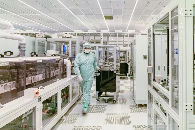 Scientist in protective gear walking in a high-tech cleanroom laboratory